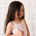 Load image into Gallery viewer, Young girl wearing a light pink floral swimsuit with delicate straps, perfect for summer swimwear
