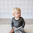 Load image into Gallery viewer, Young boy wearing a green long-sleeve shirt with sailboat and striped swimming shorts
