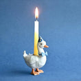 Load image into Gallery viewer, Ceramic duck cake topper holding a yellow candle, wearing a party hat and bow tie, perfect for birthday celebrations
