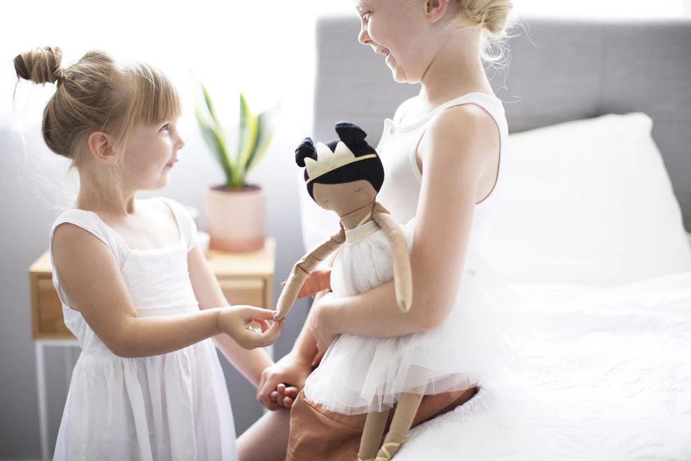 wo young girls playing with a handmade doll in a cozy bedroom setting